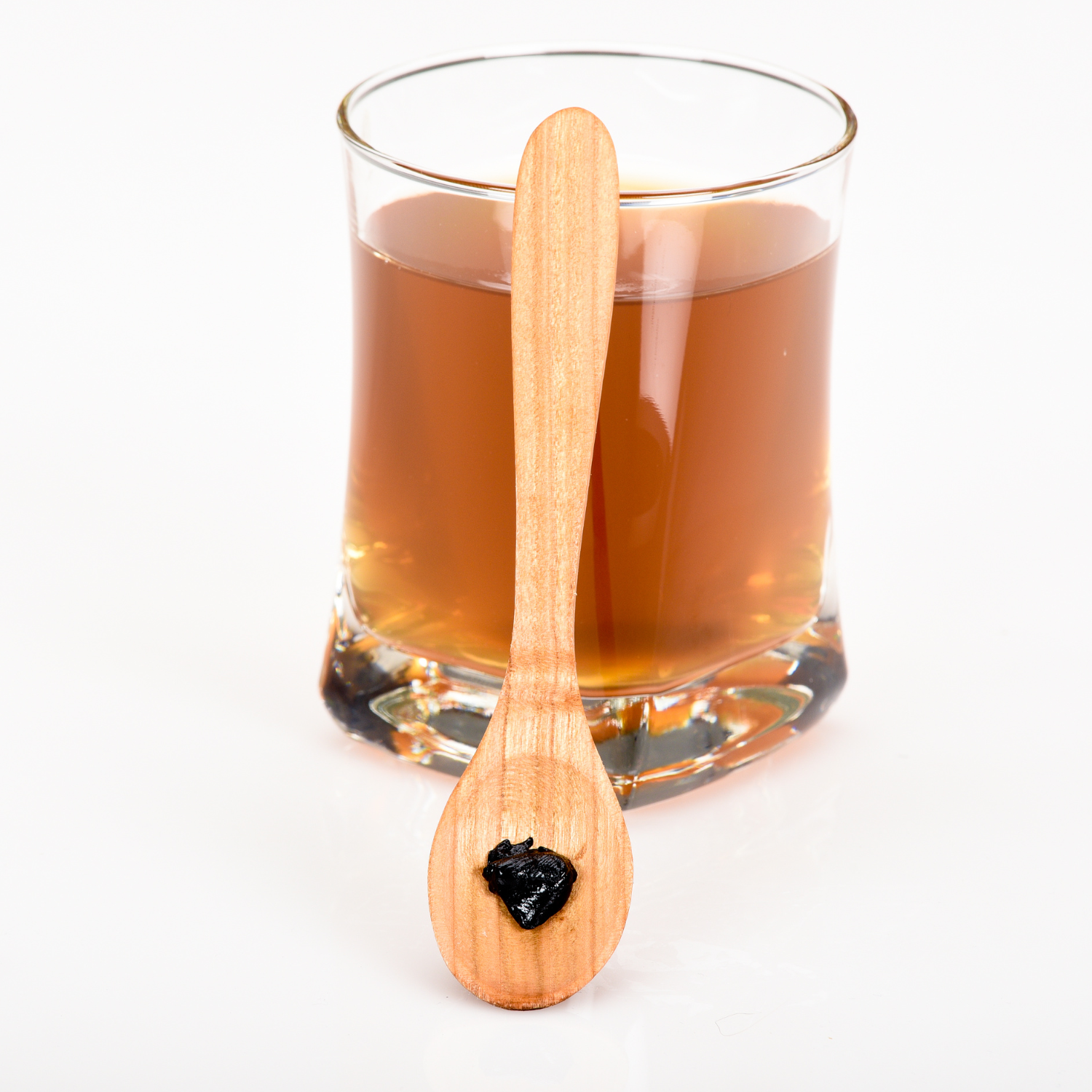 Shilajit-Harz auf Holzlöffel vor Glas mit aufgelöster Shilajit-Lösung – traditionelles Naturharz zur Unterstützung von Energie, Vitalität und Zellfunktion