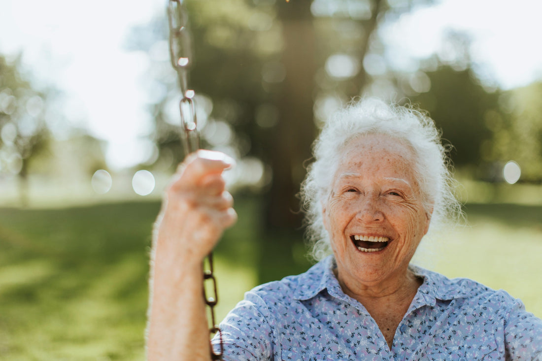 Lächelnde ältere Frau auf einer Schaukel im Freien – Symbol für Lebensfreude, Vitalität und gesundes Altern im Kontext von Longevity