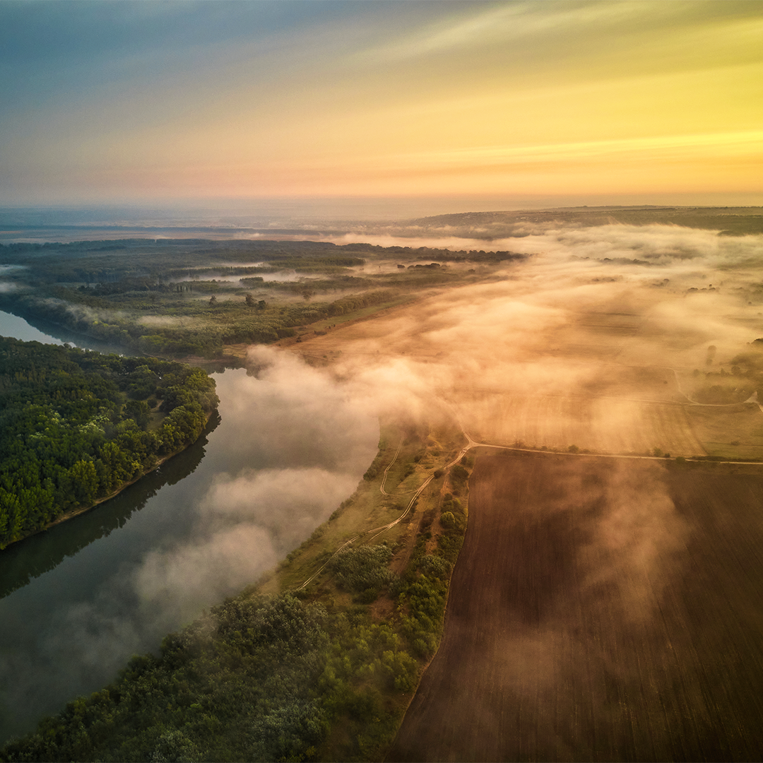 Luftaufnahme einer Flusslandschaft im Morgennebel – Symbol für Reinheit und Naturverbundenheit