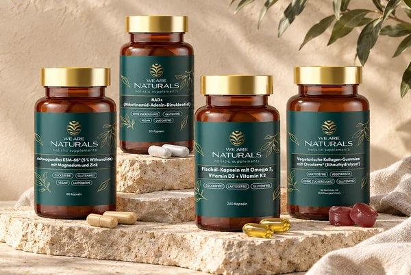 Vier Produkte von We Are Naturals auf Kalkstein mit Olivenzweigen und Leinen